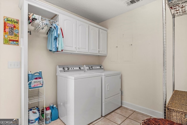 washroom featuring a textured ceiling, separate washer and dryer, cabinets, and light tile patterned floors