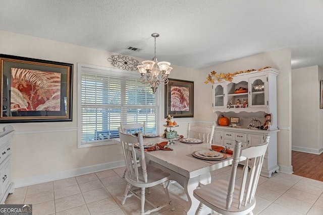 tiled dining room with an inviting chandelier and a textured ceiling