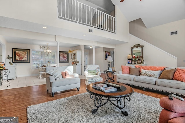 living room with a towering ceiling, light hardwood / wood-style floors, and ceiling fan with notable chandelier