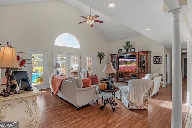 living room featuring high vaulted ceiling, decorative columns, hardwood / wood-style flooring, and ceiling fan