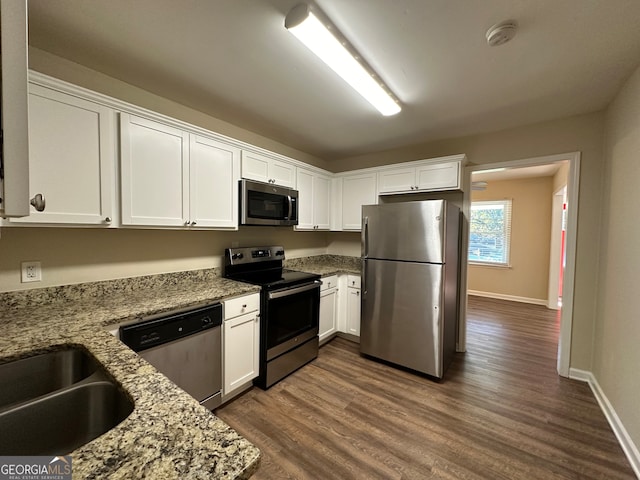 kitchen featuring light stone counters, white cabinets, sink, dark hardwood / wood-style floors, and appliances with stainless steel finishes