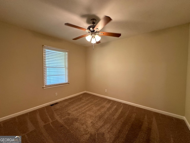 spare room with ceiling fan and dark carpet