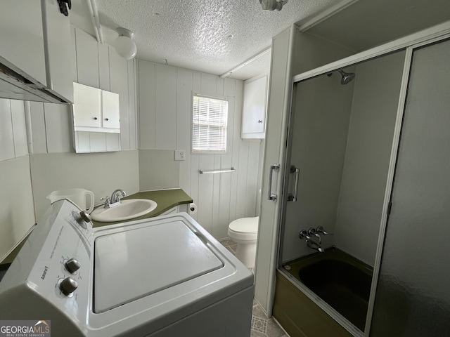 full bathroom with enclosed tub / shower combo, washer / dryer, vanity, a textured ceiling, and toilet