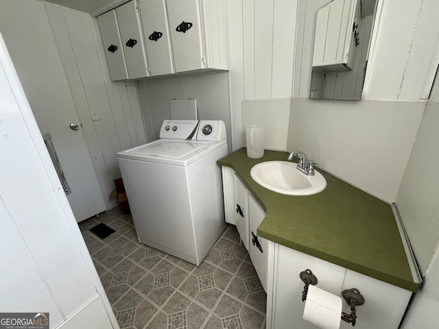 washroom with cabinets, light tile patterned flooring, sink, and washer / clothes dryer