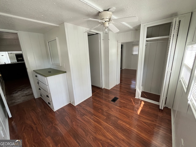 unfurnished bedroom with ceiling fan, dark hardwood / wood-style floors, a textured ceiling, and a closet