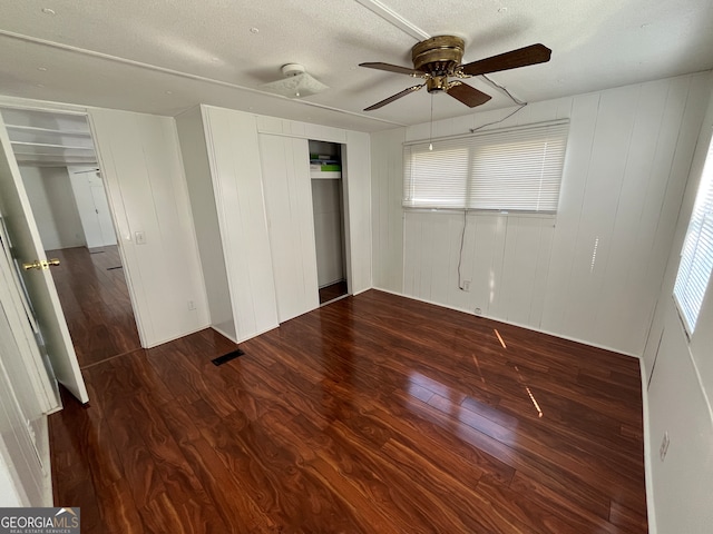 unfurnished bedroom featuring ceiling fan, dark hardwood / wood-style floors, and a textured ceiling