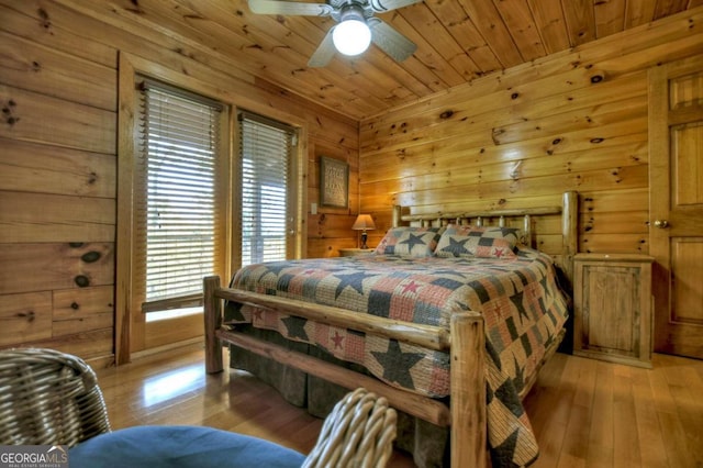 bedroom featuring light hardwood / wood-style flooring, wood walls, ceiling fan, and wood ceiling