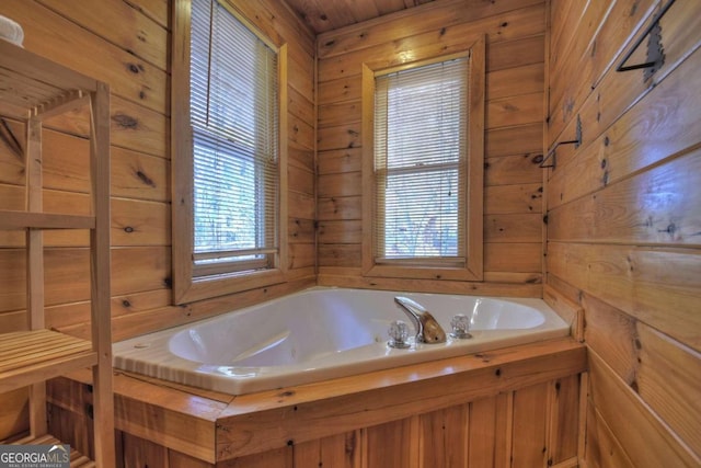 bathroom with wood walls, a tub, and plenty of natural light