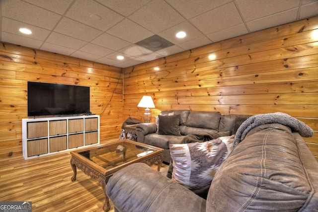 living room featuring wood walls, a drop ceiling, and hardwood / wood-style flooring