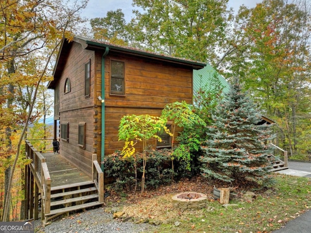 view of side of property with a deck and a fire pit