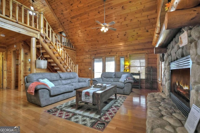 living room with a stone fireplace, high vaulted ceiling, wooden walls, hardwood / wood-style flooring, and wooden ceiling