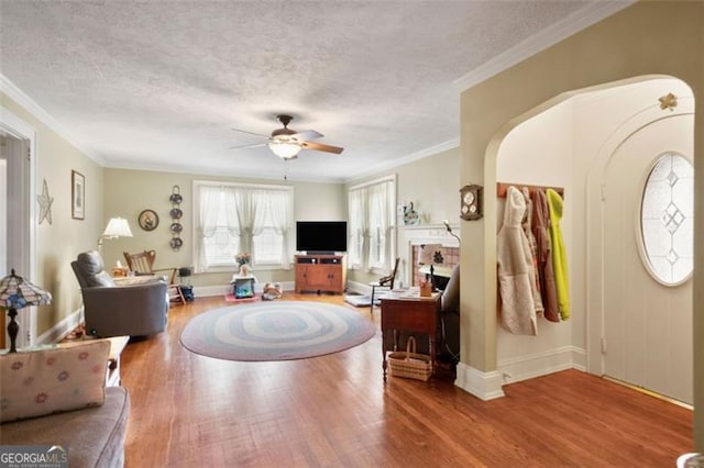 living room featuring ornamental molding, a textured ceiling, hardwood / wood-style flooring, and ceiling fan