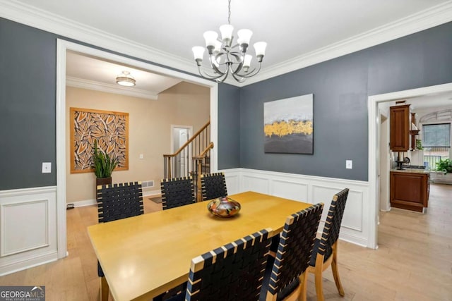 dining area featuring light hardwood / wood-style floors, an inviting chandelier, and crown molding