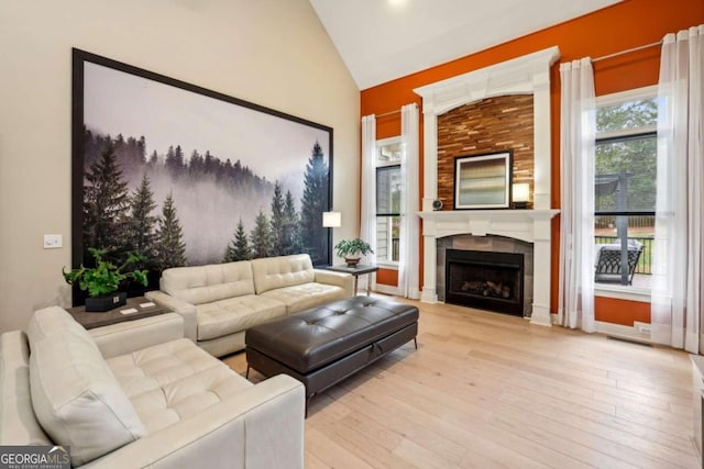 living room featuring light wood-type flooring, a fireplace, and high vaulted ceiling