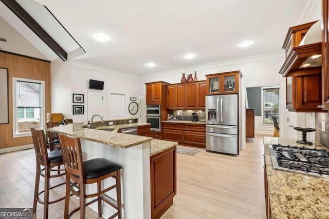 kitchen with vaulted ceiling with beams, stainless steel appliances, a kitchen bar, wooden walls, and sink