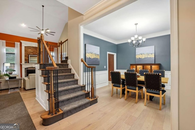 dining space with lofted ceiling, crown molding, light hardwood / wood-style floors, and ceiling fan with notable chandelier