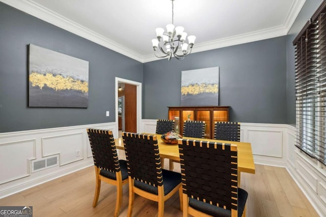 dining room featuring a chandelier, light hardwood / wood-style floors, and crown molding