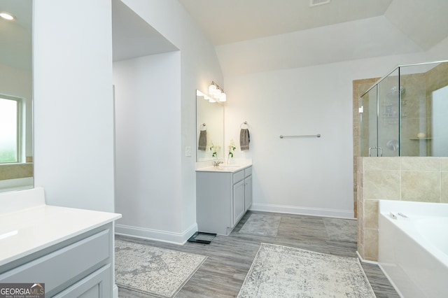 bathroom with hardwood / wood-style floors, vanity, separate shower and tub, and vaulted ceiling