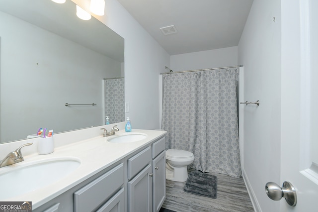 bathroom with walk in shower, vanity, hardwood / wood-style flooring, and toilet