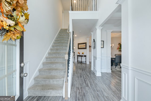 stairway with wood-type flooring and decorative columns