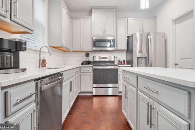 kitchen with light stone counters, stainless steel appliances, backsplash, dark hardwood / wood-style flooring, and sink