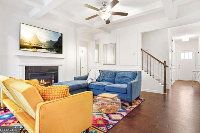 living room featuring a fireplace, dark hardwood / wood-style floors, coffered ceiling, beamed ceiling, and ceiling fan