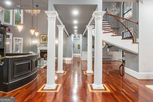 interior space featuring a high ceiling, decorative light fixtures, dark hardwood / wood-style floors, and stone countertops