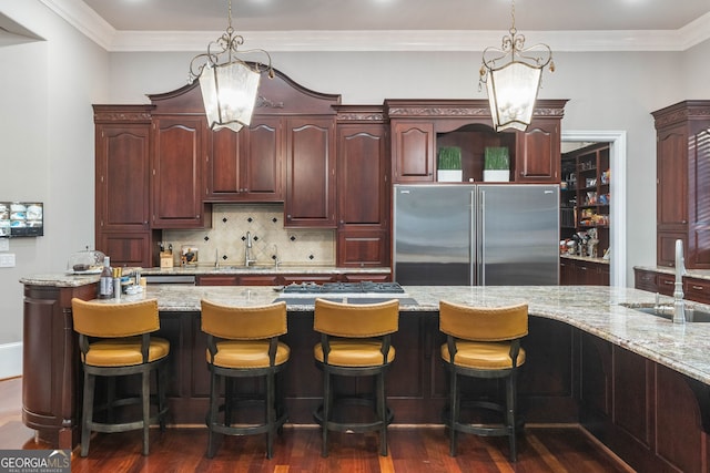 kitchen featuring sink, light stone counters, appliances with stainless steel finishes, hanging light fixtures, and dark hardwood / wood-style flooring