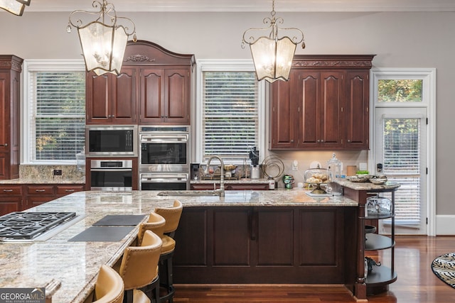 kitchen with stainless steel appliances, light stone countertops, a kitchen bar, pendant lighting, and dark hardwood / wood-style flooring