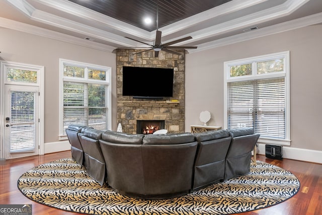 living room featuring a fireplace, ornamental molding, a raised ceiling, and hardwood / wood-style floors