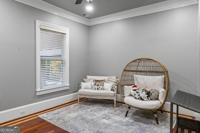 sitting room featuring hardwood / wood-style floors, ceiling fan, and crown molding