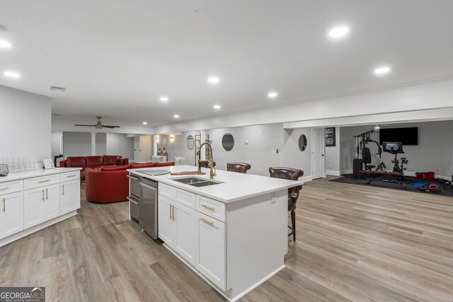 kitchen featuring white cabinetry, sink, an island with sink, light hardwood / wood-style floors, and stainless steel dishwasher