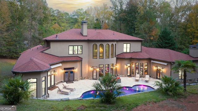 back house at dusk with french doors and a patio area