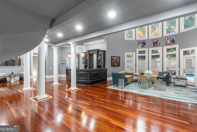 living room featuring ornate columns, hardwood / wood-style floors, and a high ceiling