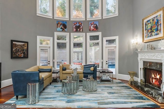 sitting room with a high ceiling, a wealth of natural light, hardwood / wood-style floors, and a fireplace