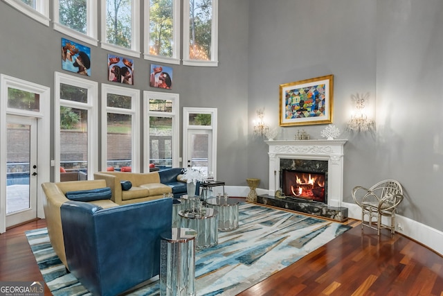 living room with plenty of natural light, hardwood / wood-style flooring, and a towering ceiling