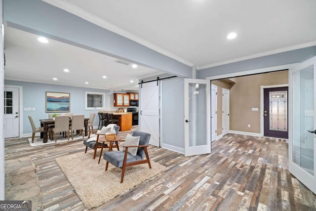 living room featuring a barn door, wood-type flooring, french doors, and ornamental molding