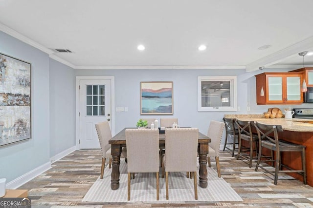 dining area with light wood-type flooring and crown molding