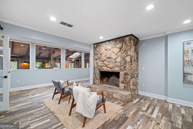 living room featuring a stone fireplace, a wealth of natural light, dark hardwood / wood-style floors, and crown molding