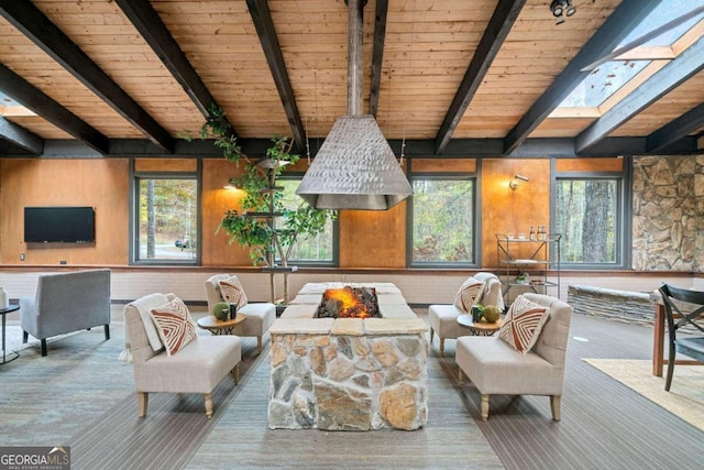 living room featuring wood walls, beamed ceiling, and a skylight