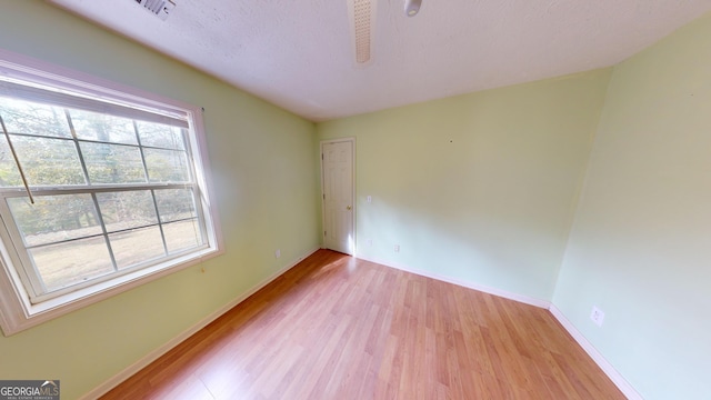 spare room with light wood-type flooring and a textured ceiling