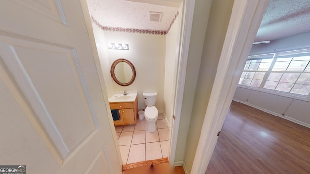 bathroom with hardwood / wood-style floors, vanity, a textured ceiling, and toilet