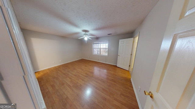 empty room featuring a textured ceiling, light hardwood / wood-style floors, and ceiling fan