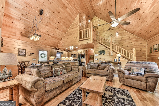 living room featuring high vaulted ceiling, light hardwood / wood-style flooring, and wooden walls