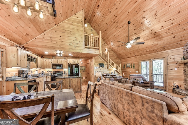 dining space with light wood-type flooring, high vaulted ceiling, wooden walls, sink, and wood ceiling