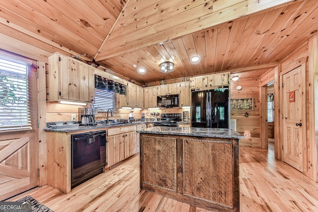 kitchen featuring black appliances, a kitchen island, light wood-type flooring, and wooden walls