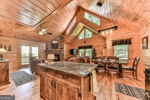 kitchen with high vaulted ceiling, wooden walls, wood ceiling, a skylight, and light hardwood / wood-style flooring