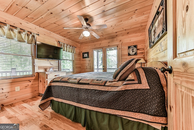 bedroom featuring french doors, wood walls, light hardwood / wood-style floors, wooden ceiling, and ceiling fan