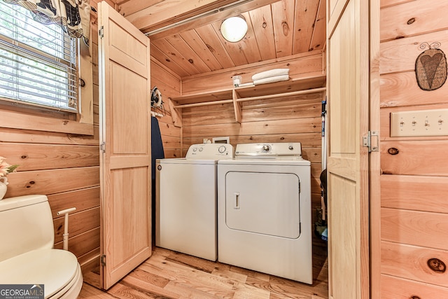 laundry room featuring wood walls, washing machine and clothes dryer, wooden ceiling, and light hardwood / wood-style floors