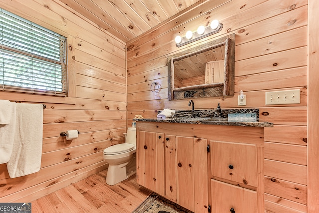 bathroom with wooden ceiling, hardwood / wood-style flooring, vanity, wooden walls, and toilet